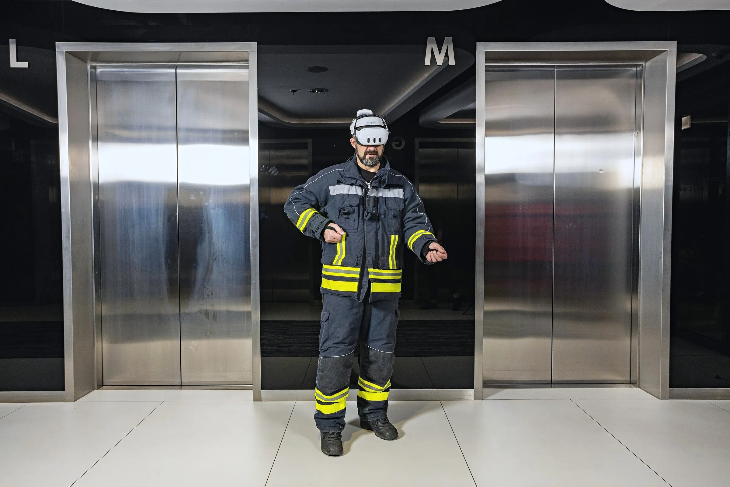 Pompier en tenue d’intervention portant un casque VR devant des ascenseurs