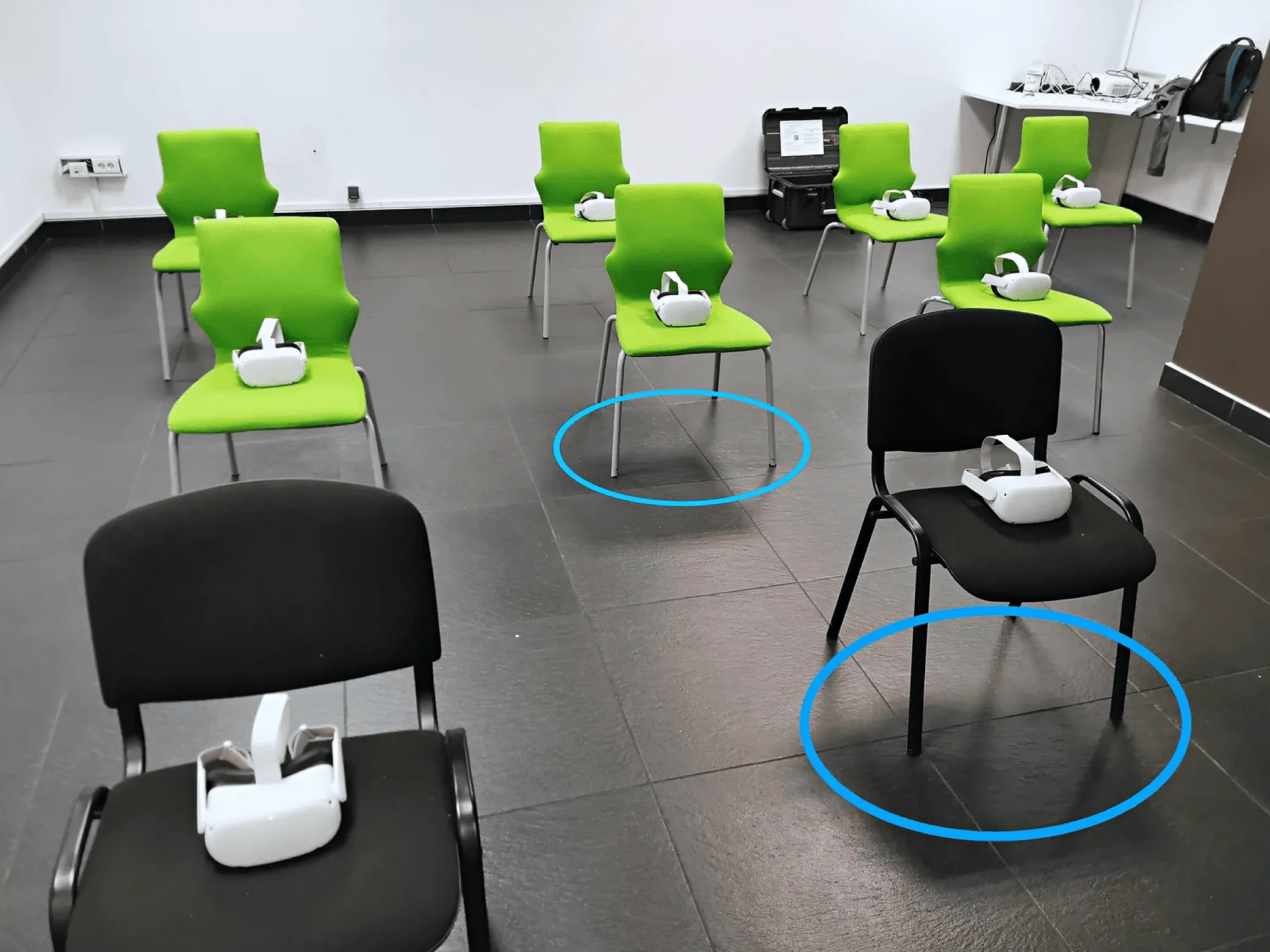 Sala szkoleniowa z krzesłami, na których leżą gogle VR; niebieskie okręgi na podłodze oznaczają stacjonarną strefę bezpieczeństwa każdego stanowiska