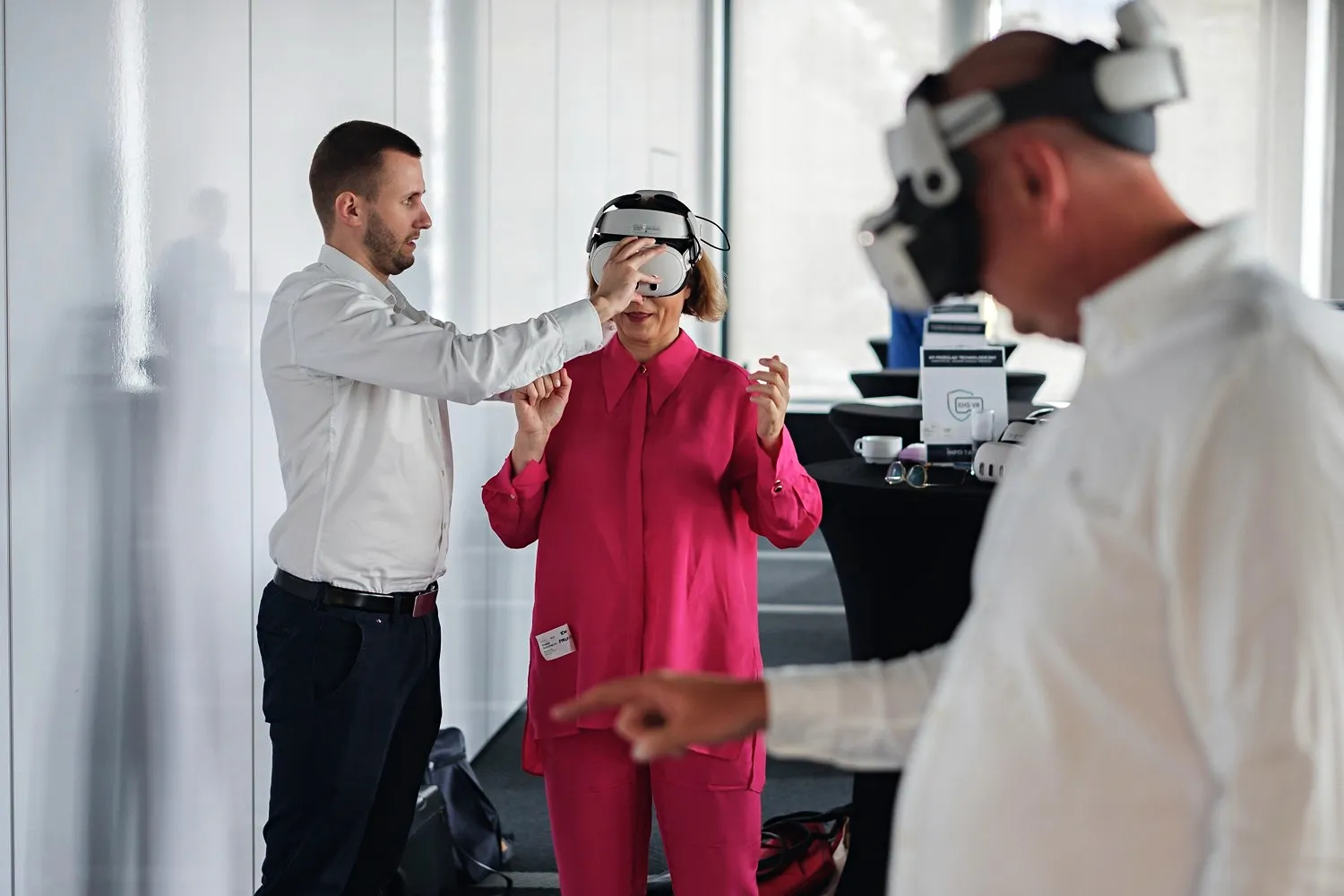 Une femme en chemise rose, un homme en chemise blanche et un spécialiste SST présentent la technologie VR.