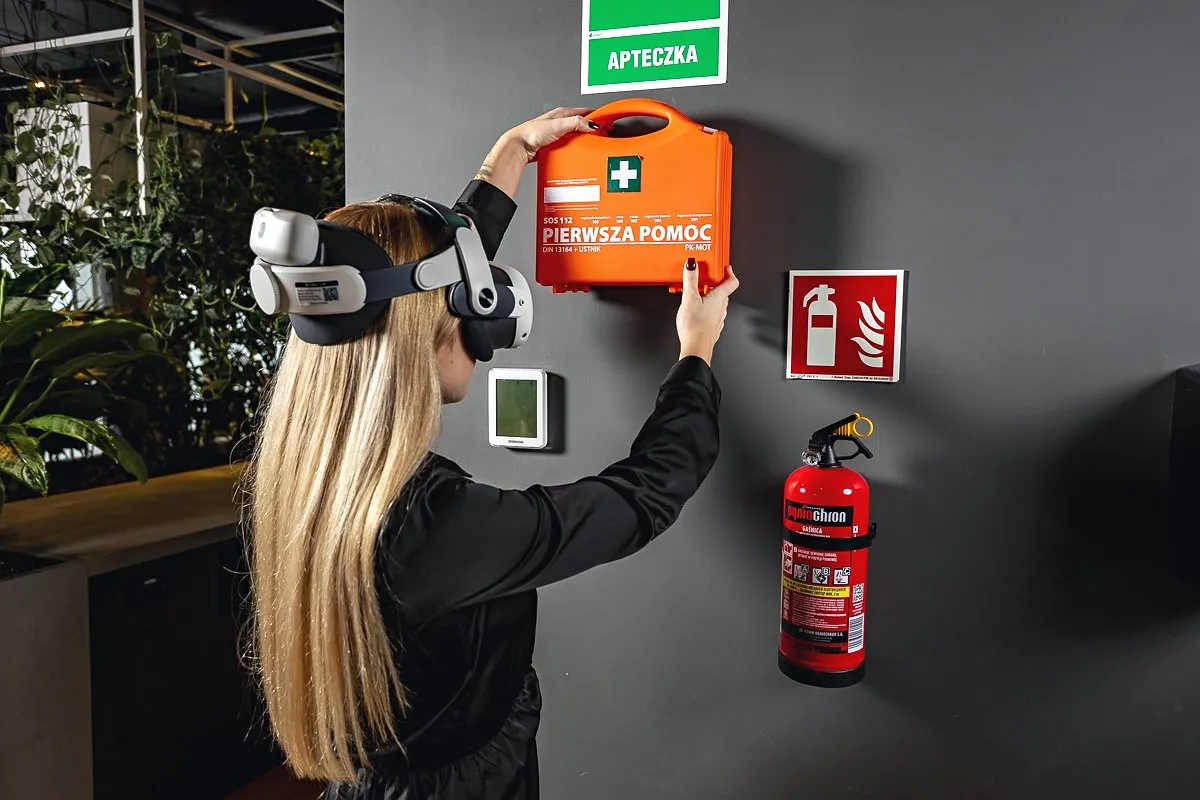 Trainee in a VR headset next to a first aid kit and a fire extinguisher