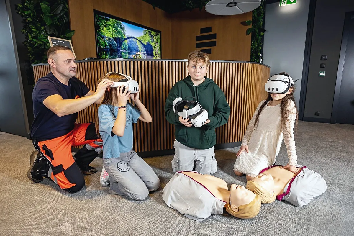 A paramedic helps a child put on a VR headset during first aid training