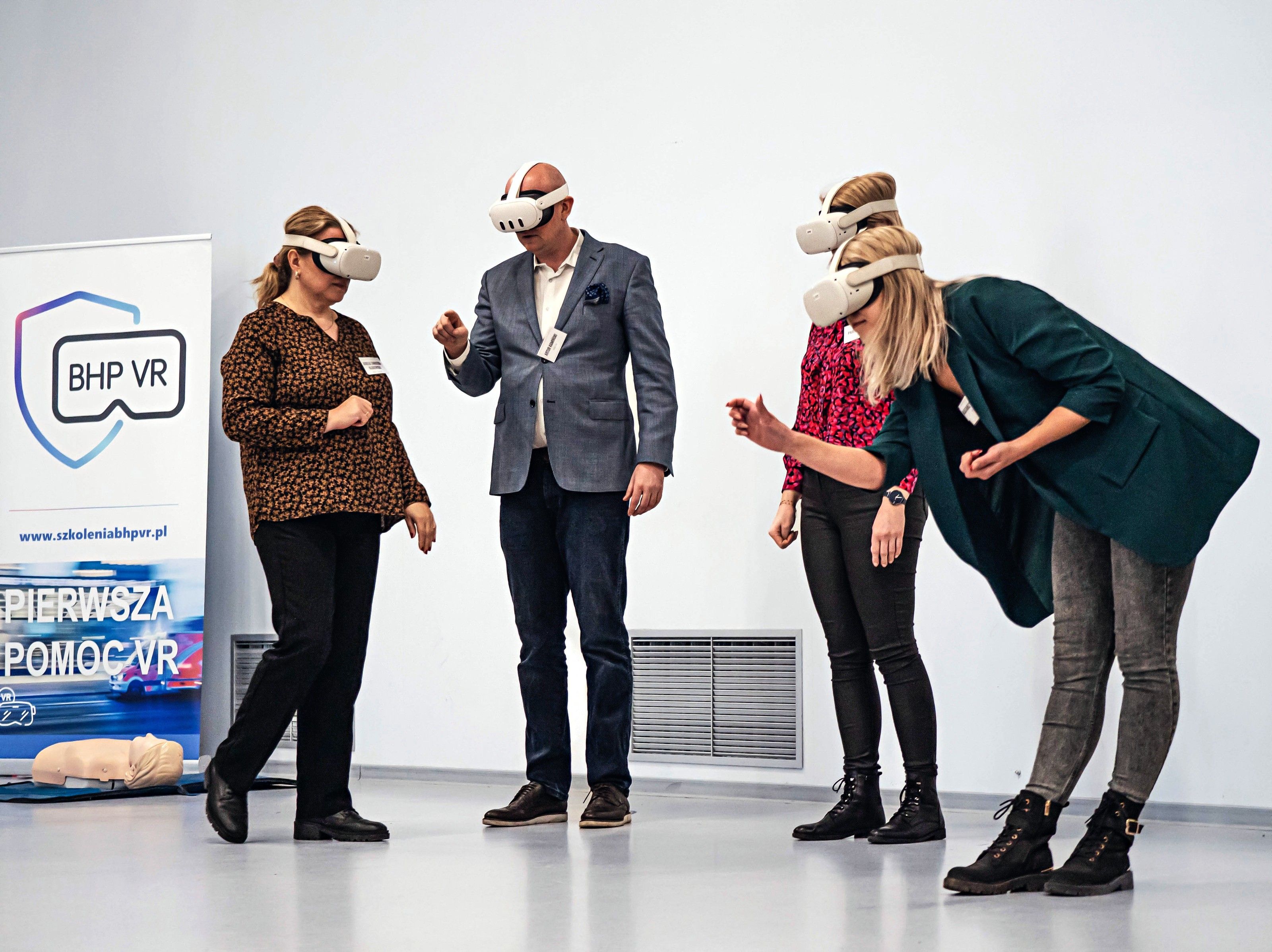 Participants train in VR headsets at a safety event, next to a first aid in VR banner